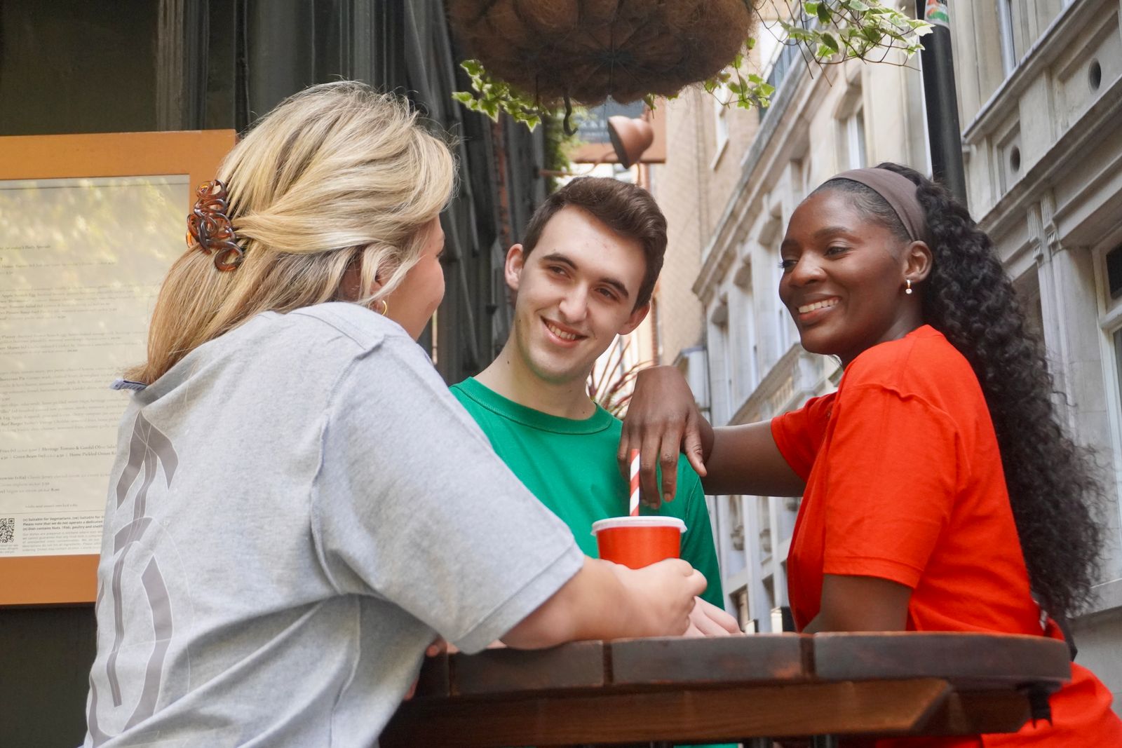 Three people sitting at an outdoor table, enjoying drinks together.